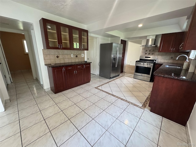 28240 Lahser Rd, Southfield, MI 48034 - kitchen with appliances with stainless steel finishes, wall chimney range hood, light tile patterned floors, decorative backsplash, and dark stone counters