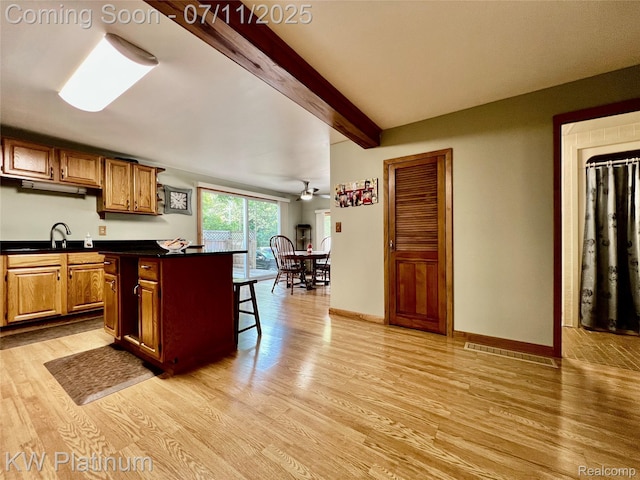 2243 Sunnyside Rd, Kimball, MI 48074 - kitchen with dark countertops, light wood-style flooring, a breakfast bar, beamed ceiling, and a center island