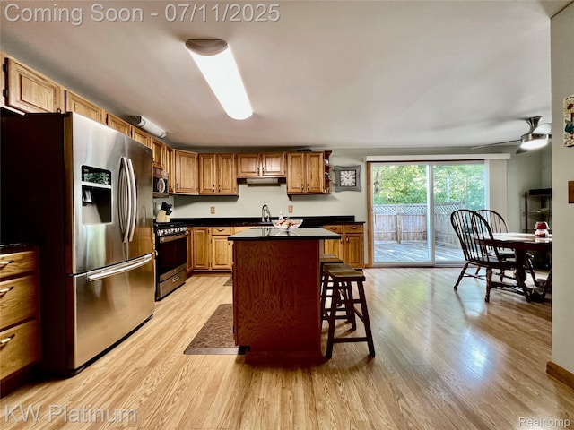 2243 Sunnyside Rd, Kimball, MI 48074 - kitchen with stainless steel appliances, dark countertops, light wood-style flooring, a kitchen island with sink, and a kitchen bar