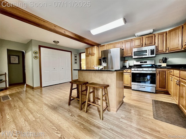 2243 Sunnyside Rd, Kimball, MI 48074 - kitchen with stainless steel appliances, light wood-style floors, a breakfast bar area, dark countertops, and beam ceiling