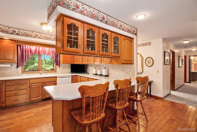10363 E Bristol Rd, Davison, MI 48423 - kitchen with light countertops, a breakfast bar area, decorative backsplash, white dishwasher, and glass insert cabinets