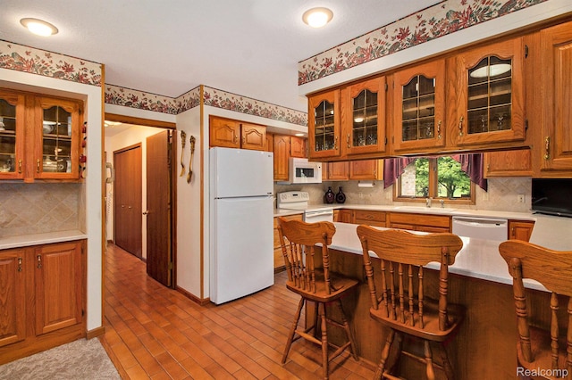 10363 E Bristol Rd, Davison, MI 48423 - kitchen with white appliances, brown cabinetry, light countertops, and tasteful backsplash