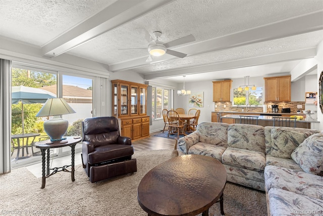 17729 Harman St, Melvindale, MI 48122 - living area featuring a textured ceiling, beam ceiling, ceiling fan, light wood-style flooring, and a chandelier