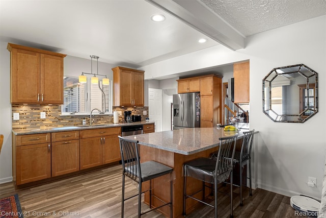 17729 Harman St, Melvindale, MI 48122 - kitchen with appliances with stainless steel finishes, brown cabinets, a peninsula, wood finished floors, and a kitchen bar