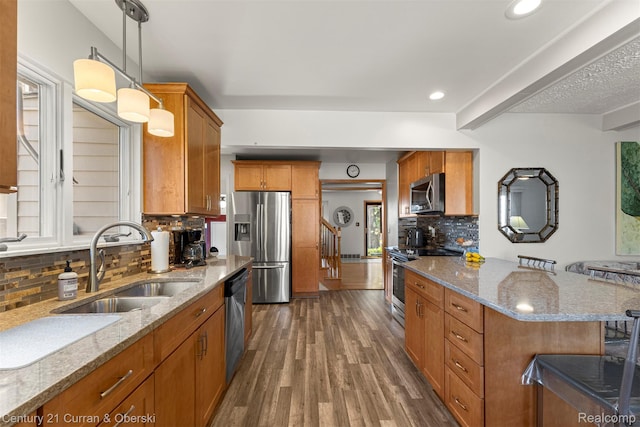 17729 Harman St, Melvindale, MI 48122 - kitchen featuring stainless steel appliances, brown cabinets, wood finished floors, light stone counters, and decorative backsplash