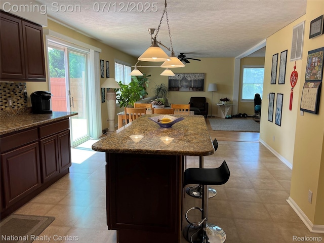 38443 Meghan Ln, Westland, MI 48185 - kitchen with a breakfast bar, a textured ceiling, ceiling fan, a center island, and backsplash