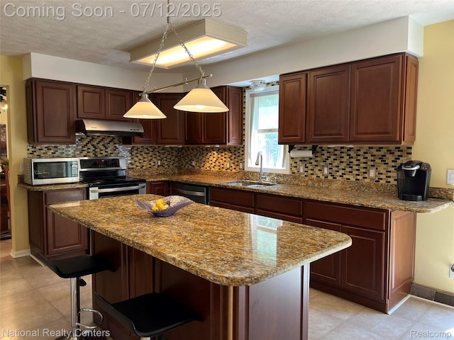 38443 Meghan Ln, Westland, MI 48185 - kitchen featuring stainless steel appliances, under cabinet range hood, a textured ceiling, a breakfast bar area, and decorative backsplash
