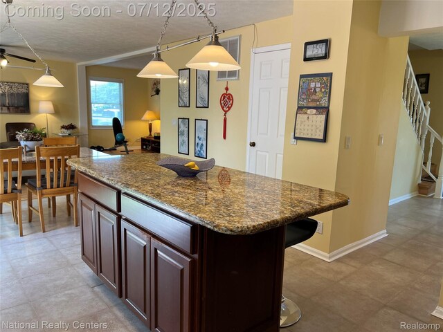 38443 Meghan Ln, Westland, MI 48185 - kitchen with a breakfast bar, a textured ceiling, a ceiling fan, dark stone countertops, and a center island