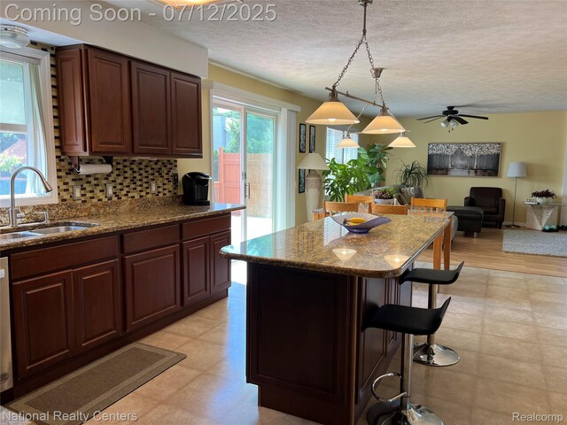 38443 Meghan Ln, Westland, MI 48185 - kitchen featuring a breakfast bar, backsplash, light floors, a textured ceiling, and dark stone counters