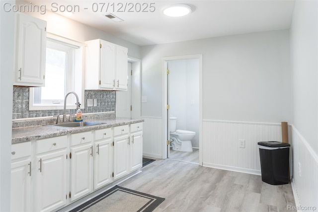 14778 Harrison St, Livonia, MI 48154 - kitchen with light wood-type flooring, wainscoting, white cabinetry, light countertops, and tasteful backsplash