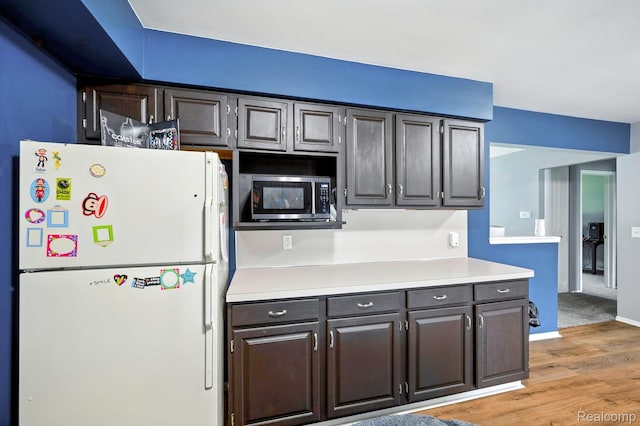 803 S Dayton St, Davison, MI 48423 - kitchen with freestanding refrigerator, stainless steel microwave, light wood-style flooring, and light countertops