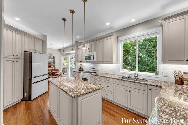 13400 Ravine View Dr, Grand Haven, MI 49417 - kitchen featuring white appliances, light wood-type flooring, backsplash, a center island, and recessed lighting