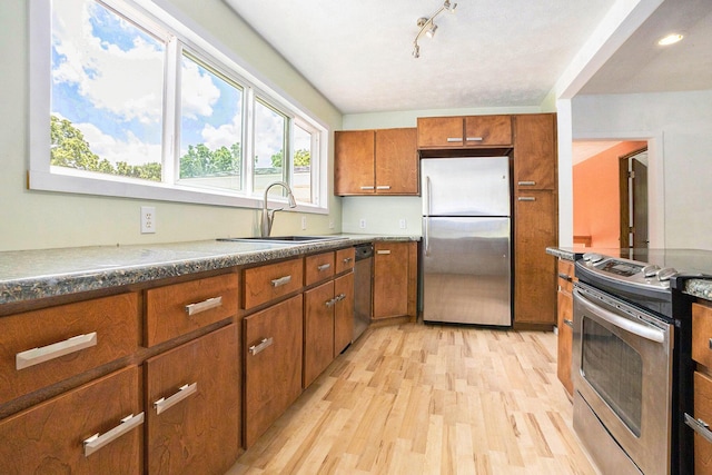 3345 Harmony Rd, Hopkins, MI 49328 - kitchen with stainless steel appliances, brown cabinetry, and light wood-type flooring