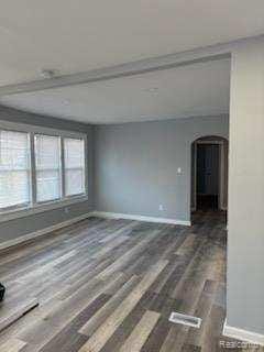 14557 Strathmoor St, Detroit, MI 48227 - spare room featuring arched walkways and dark wood-type flooring