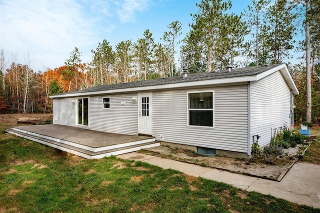 1134 Wagon Wheel Ln, Interlochen, MI 49643 - back of property featuring a wooden deck, a yard, and a shingled roof