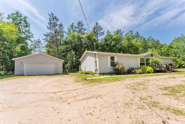 1134 Wagon Wheel Ln, Interlochen, MI 49643 - view of front of property featuring a garage, an outbuilding, and view of wooded area
