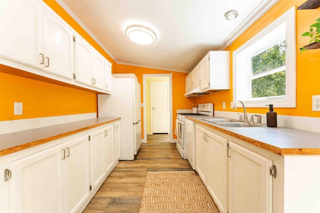 1134 Wagon Wheel Ln, Interlochen, MI 49643 - kitchen with white appliances, white cabinets, light wood-style floors, crown molding, and light countertops