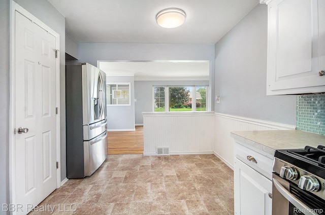 2890 Maxwell St, Trenton, MI 48183 - kitchen with appliances with stainless steel finishes, light countertops, stone finish flooring, white cabinets, and a wainscoted wall