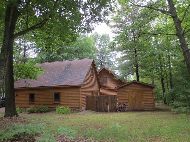 6325 Big Bay Rd, Bear Lake, MI 49614 - view of side of home featuring a storage shed, roof with shingles, and log veneer siding