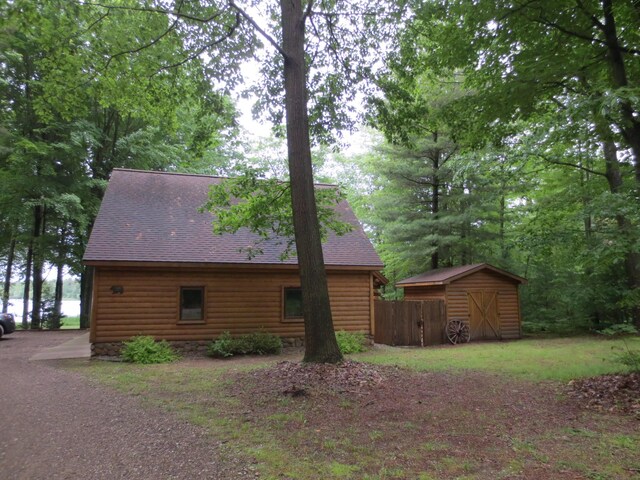 6325 Big Bay Rd, Bear Lake, MI 49614 - view of side of property featuring a storage shed, a shingled roof, and faux log siding