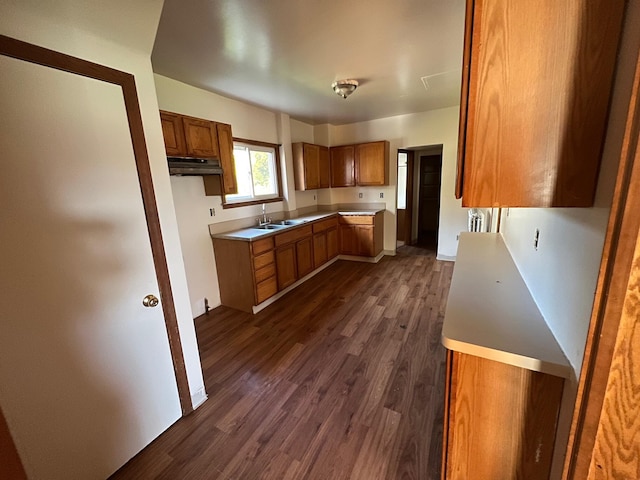 611 Steward Ave, Jackson, MI 49202 - kitchen featuring brown cabinetry, dark wood-type flooring, light countertops, and under cabinet range hood