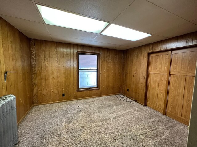611 Steward Ave, Jackson, MI 49202 - unfurnished bedroom with radiator heating unit, carpet floors, a drop ceiling, wooden walls, and a closet