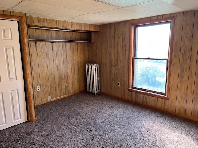 611 Steward Ave, Jackson, MI 49202 - unfurnished room featuring radiator, dark carpet, and wooden walls