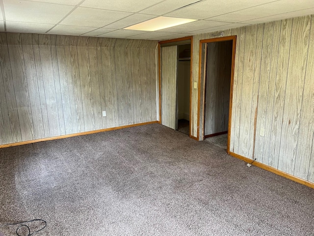 611 Steward Ave, Jackson, MI 49202 - unfurnished bedroom with carpet, a paneled ceiling, and wood walls