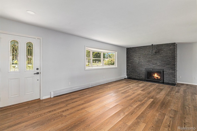 2145 Helmsford Dr, Wolverine Lake, MI 48390 - unfurnished living room with hardwood / wood-style floors, a stone fireplace, and a baseboard heating unit