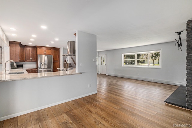 2145 Helmsford Dr, Wolverine Lake, MI 48390 - kitchen featuring stainless steel fridge with ice dispenser, wall chimney exhaust hood, wood finished floors, light stone counters, and recessed lighting