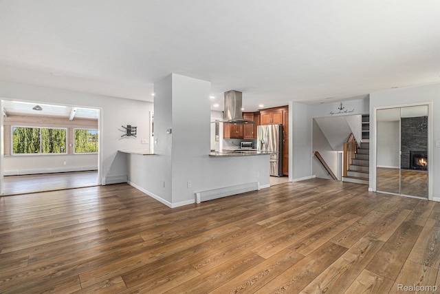 2145 Helmsford Dr, Wolverine Lake, MI 48390 - unfurnished living room with wood-type flooring, stairway, a baseboard radiator, a large fireplace, and recessed lighting