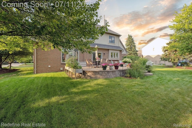47451 Wallingford Ct, Canton, MI 48188 - back of property at dusk with brick siding, a yard, a patio, and a chimney