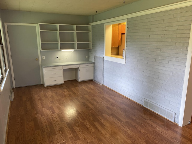 6832 Oakland Dr, Portage, MI 49024 - unfurnished office featuring built in study area, brick wall, and dark wood finished floors
