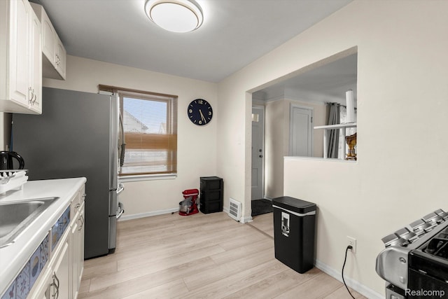 18291 Henry St, Melvindale, MI 48122 - kitchen with white cabinetry, light wood-style floors, freestanding refrigerator, and light countertops