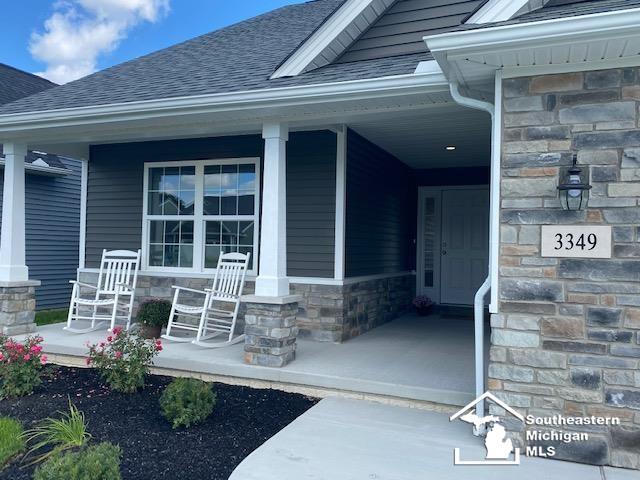 8260 Grande Lake Cir, Temperance, MI 48182 - entrance to property featuring a porch, a shingled roof, and stone siding