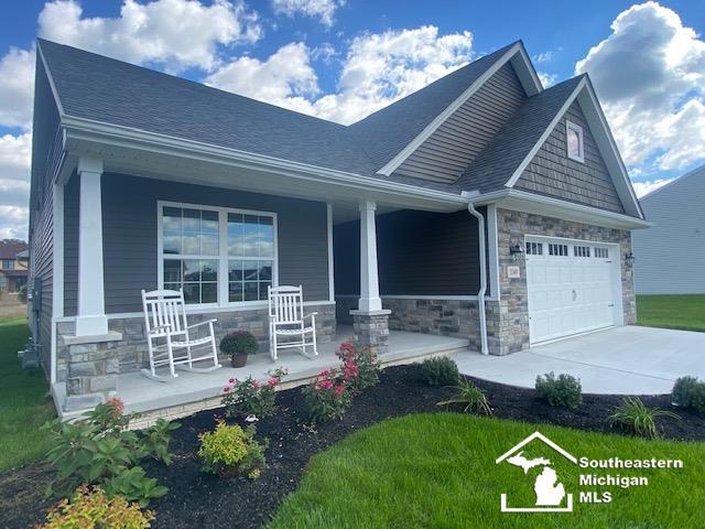8260 Grande Lake Cir, Temperance, MI 48182 - craftsman inspired home featuring covered porch, stone siding, an attached garage, driveway, and a shingled roof