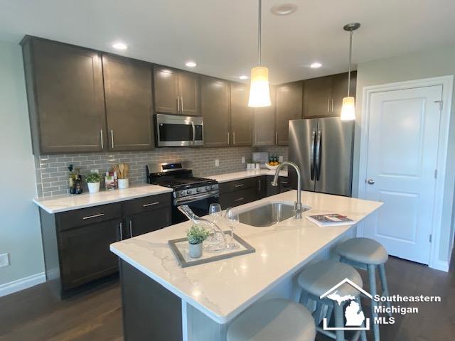 8260 Grande Lake Cir, Temperance, MI 48182 - kitchen featuring appliances with stainless steel finishes, tasteful backsplash, a kitchen bar, pendant lighting, and recessed lighting
