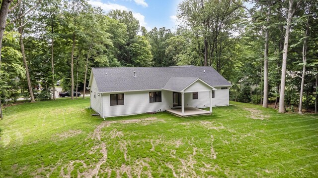 9841 Beech Tree Ln, Frankenmuth, MI 48734 - back of property featuring a shingled roof, a yard, and view of scattered trees