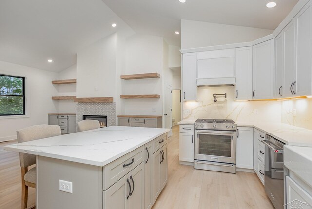 9841 Beech Tree Ln, Frankenmuth, MI 48734 - kitchen featuring appliances with stainless steel finishes, open shelves, vaulted ceiling, light wood-style floors, and a fireplace