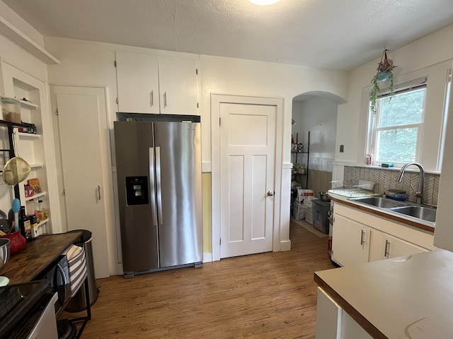 3925 Miramar Ave NE, Grand Rapids, MI 49525 - kitchen with stainless steel fridge with ice dispenser, arched walkways, light wood-type flooring, white cabinetry, and light countertops
