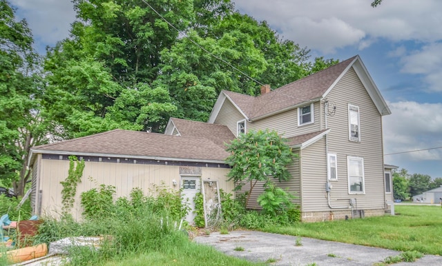 1085 E Chicago Rd Unit A, Quincy, MI 49082 - view of front of house with a shingled roof, a chimney, and a front lawn
