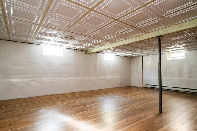 6828 First Ave, Coloma, MI 49038 - below grade area with a baseboard radiator, hardwood / wood-style floors, and an ornate ceiling