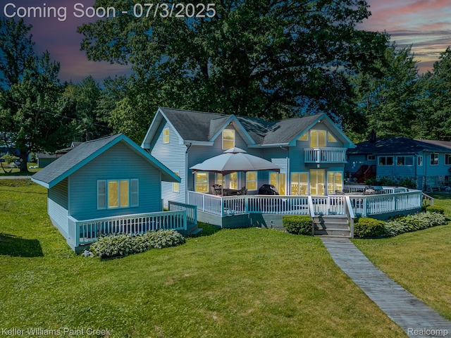 1379 Sioux St, Gladwin, MI 48624 - back of house at dusk featuring a deck, a lawn, and a balcony