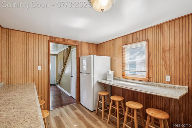 1472 Ready Ave, Burton, MI 48529 - kitchen with freestanding refrigerator, wood finished floors, a kitchen bar, and wooden walls