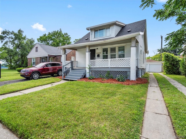 12667 Lauder St, Detroit, MI 48227 - bungalow with covered porch, asphalt driveway, a front yard, an outbuilding, and a garage