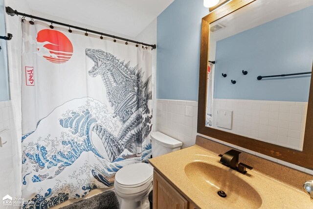 6494 W Coldwater Rd, Flushing, MI 48433 - full bath with vanity, tile walls, curtained shower, and wainscoting