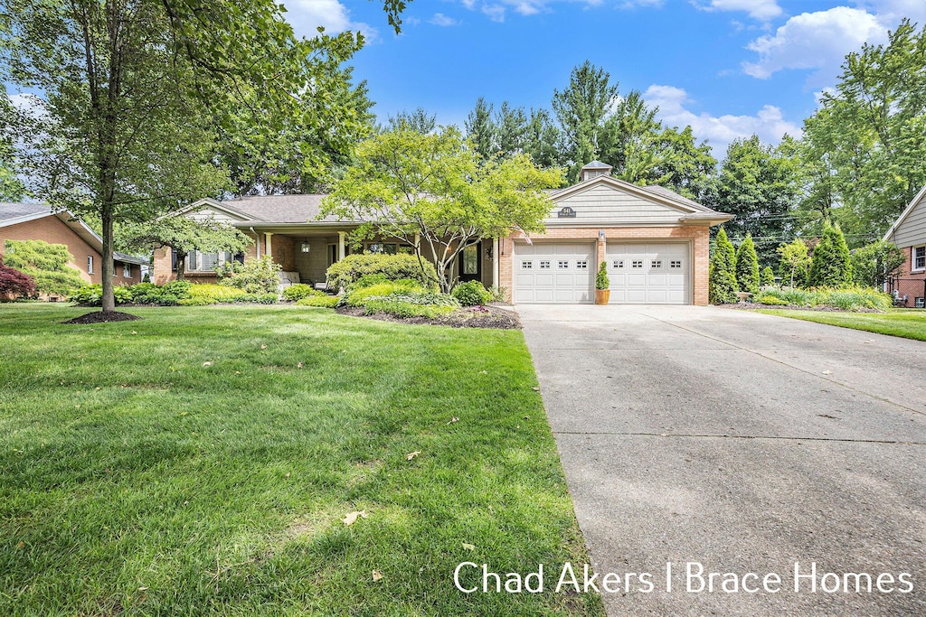 541 Russwood St NE, Grand Rapids, MI 49505 - view of front of property featuring a garage, concrete driveway, brick siding, a front lawn, and a chimney
