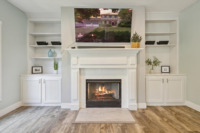 7987 36th St SE, Ada, MI 49301 - unfurnished living room featuring wood finished floors, a tile fireplace, and built in shelves