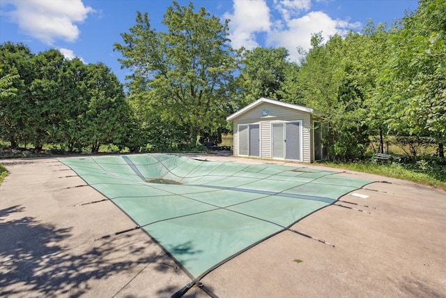 7987 36th St SE, Ada, MI 49301 - view of pool featuring an outbuilding, a covered pool, a patio area, and view of wooded area