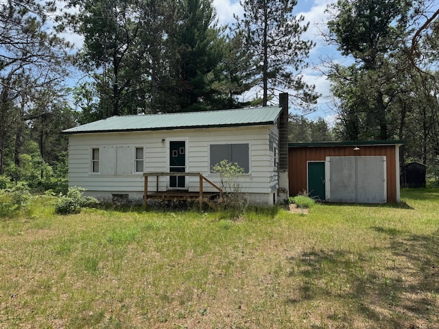 4231 W 5 Mile Rd, Irons, MI 49644 - view of front of home with a chimney, a metal roof, an outbuilding, and a front yard